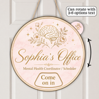 A round hanging personalized sign with a pale pink marble background and gold illustration of a brain, flowers, and stars. The sign reads 'Sophia's Office' and 'Mental Health Coordinator / Scheduler' with 'Come on in' at the bottom.