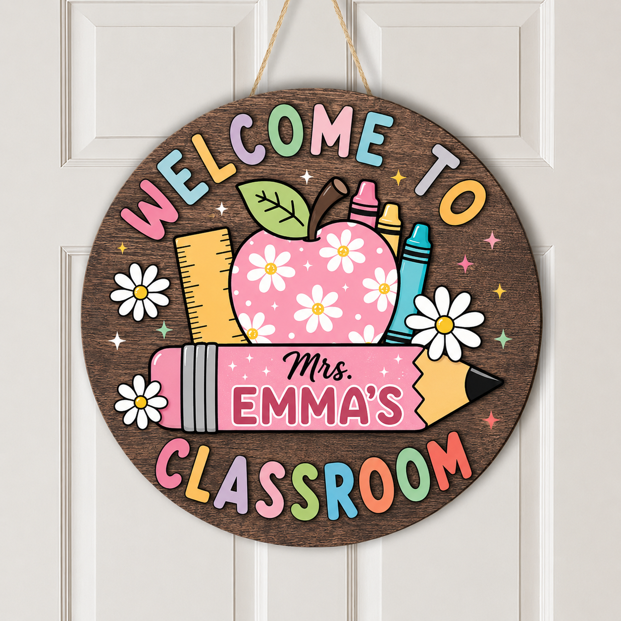 A round wooden hanging sign with a colorful school-themed design that reads 'WELCOME TO Mrs. EMMA'S CLASSROOM.